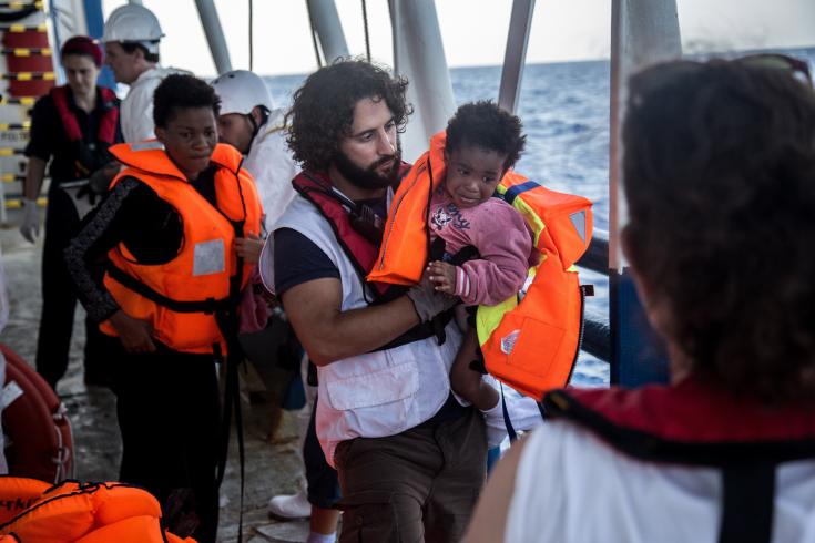 Juan Mátias Gil, coordinador general del barco Dignity I, ayuda a subir a bordo a Richard, de Nigeria, recién rescatado junto a sus padres de un bote a punto de hundirse en el mar Mediterráneo. Septiembre de 2015.