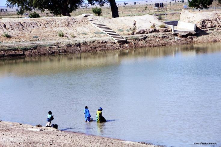 Niños recogiendo agua del lago artificial o 