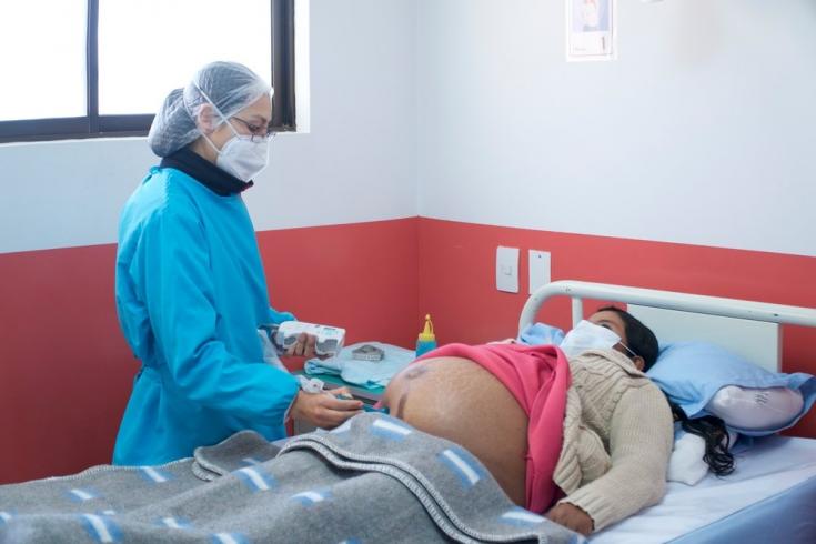 Una de nuestras médicas revisa a una paciente que está comenzando su trabajo de parto en el Centro de Salud San Roque de la ciudad de El Alto, Bolivia. Abril de 2021
