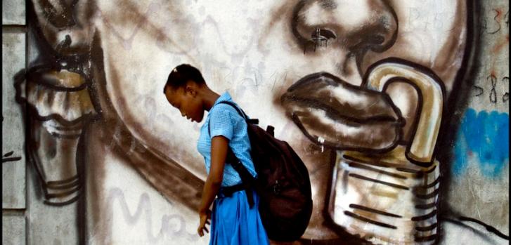 Una alumna de una escuela femenina en Puerto Príncipe pasa junto a un mural que representa la represión de las mujeres en Haití. (Grafiti de Jerry Rosembert) ©Patrick Farrell