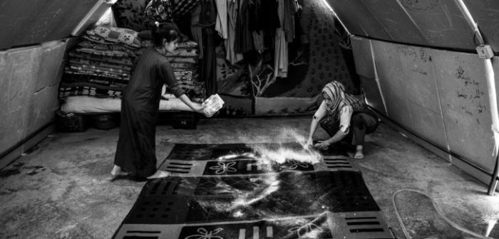 Dos niñas iraquíes limpian la alfombra de la carpa en la que viven con su familia en el campo de Bardarash, en el kurdistán iraquí  ©Manu Brabo/MEMO