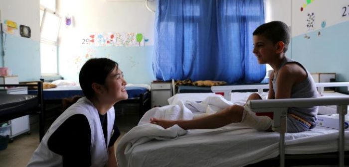 Sunyoung Park (instrumentadora quirúrgica) haciéndole compañía a un chico sirio en tratamiento en el hospital de Ramtha.Joosarang Lee/MSF