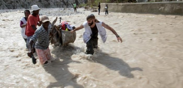 Adrien, Alejandro Hinojosa (especialista en agua y saneamiento de MSF) y Cassandre Saint-Hubert (enfermera de MSF) llevan equipamiento médico para hacer una clínica móvil del otro lado del río cerca de Seche, Port-a-Piment, Haití. ©Joffrey Monnier/MSF