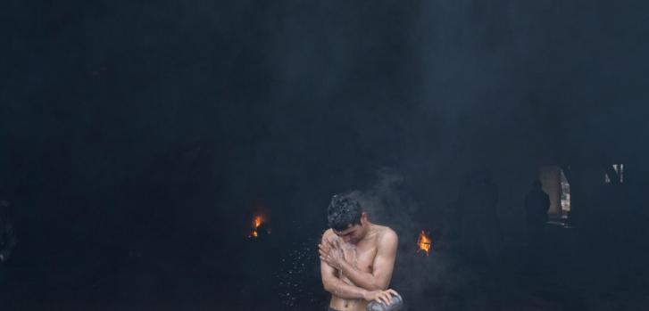 Un hombre se baña en un viejo depósito ferroviario abandonado que los refugiados y migrantes usan como albergue temporario, en Belgrado, Serbia ©Marko Drobnjakovic