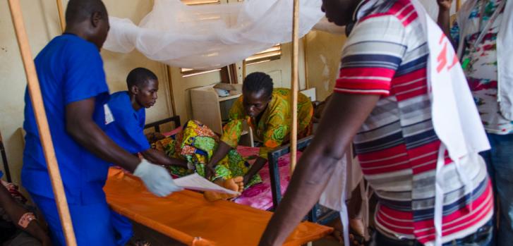 Un paciente en la sala de cirugía del hospital de Bangassou es transportado, por personal de MSF y local, de vuelta a su cama. ©Natacha Buhler/MSF