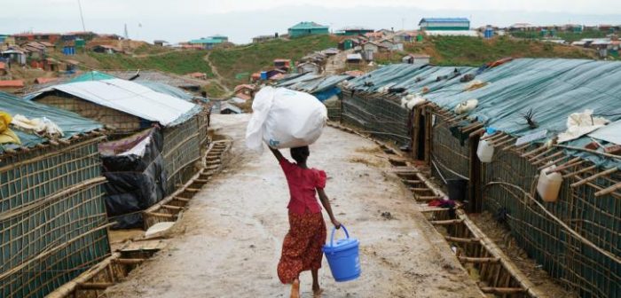 Una niña carga un balde de agua y otros artículos donados por la ONU a través de las calles mojadas del campamento de Balukhali. Los monzones causaron desastres en las comunidades locales, lo que provocó deslizamientos de tierra e incendios, lesiones, muertes y destrucción de infraestructura. Los suministros de agua se contaminaron, lo que es un riesgo para la salud pública. Dalila Mahdawi/MSF