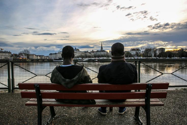 Dos migrantes descansan frente al río Adour en Bayona, justo al otro lado de la frontera con España.