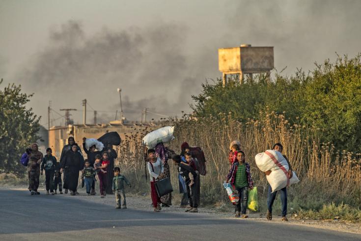 Civiles sirios, tanto árabes como kurdos, huyen con sus pertenencias debido a los bombardeos turcos en la ciudad de Ras al Ain, en la provincia de Hasakeh, a lo largo de la frontera turca, el 9 de octubre de 2019.