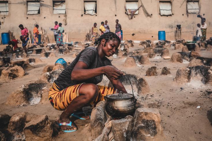 Una joven prepara una cena para su familia en un área de cocina al aire libre del campamento de Abagana para personas desplazadas en el estado de Benue. Nigeria, junio de 2020.
