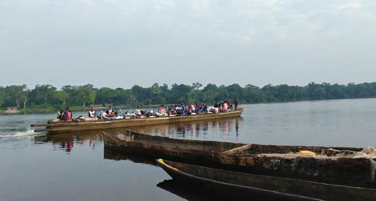 Un equipo de vacunación y sus bicicletas son transportadas río abajo en un bote de piragua.