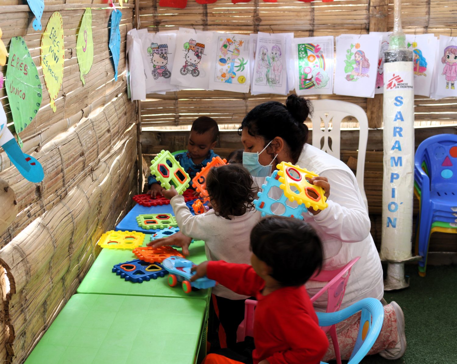 Miembro de MSF junto a niños migrantes, provenientes de Venezuela en el espacio lúdico de la clínica de MSF.