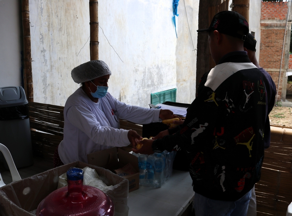Integrante del área de hidratación de MSF entrega a migrantes de Venezuela un kit de alimentos.