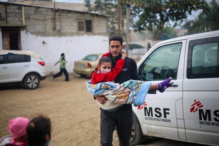 Un hombre en Gaza lleva en brazos a una niña