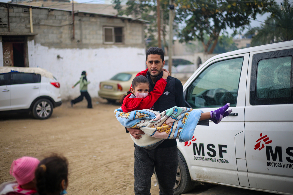 Un hombre en Gaza lleva en brazos a una niña que necesita ayuda médica.