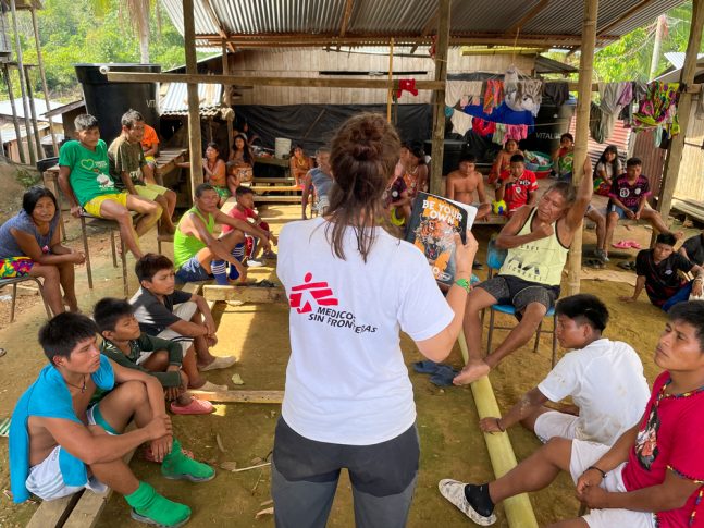 Mujer de espaldas hablando con un grupo de niños y niñas en Colombia