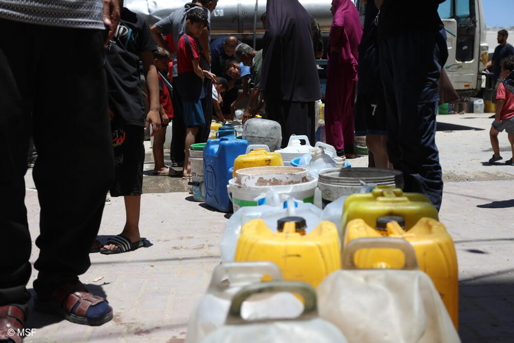 Los palestinos desplazados en Gaza hacen fila con sus bidones vacíos para obtener agua. Llegar a estos puntos supone un largo viaje bajo el calor extremo del verano, y la cantidad que reciben es mínima. Las siete unidades de tratamiento de MSF solo pueden atender a una pequeña parte de los 2,2 millones de personas que se enfrentan a una escasez deliberada de recursos hídricos.