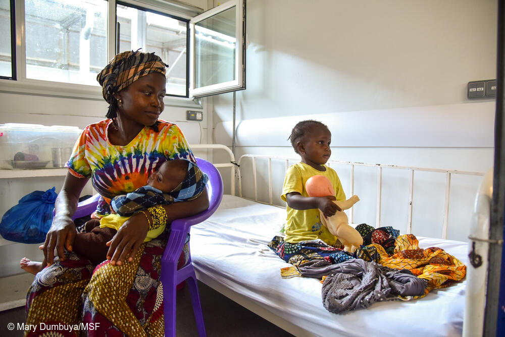 Fanta Morri, de 3 años, sostiene una muñeca en la sala de hospitalización del Hospital Materno-Infantil de MSF en Kenema, Sierra Leona. Acompaña a su madre, Umu Morri, de 25 años, y a su hermana Ramatu, de 8 meses, que está recibiendo tratamiento por fiebre y diarrea frecuente.