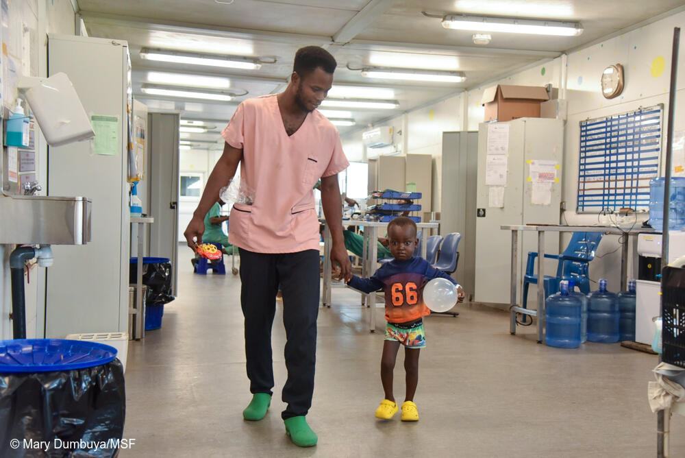 El consejero de MSF Kemoh Kargbo sostiene la mano de Michael Lagbay, de 3 años, en la sala de pediatría del Hospital Materno-Infantil de MSF en Kenema, Sierra Leona.