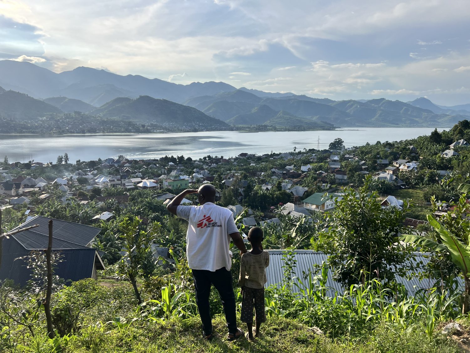 Un miembro de MSF y un niño contemplan la ciudad de Minova y el lago Kivu desde lo alto de una colina en la provincia de Kivu del Sur, República Democrática del Congo.