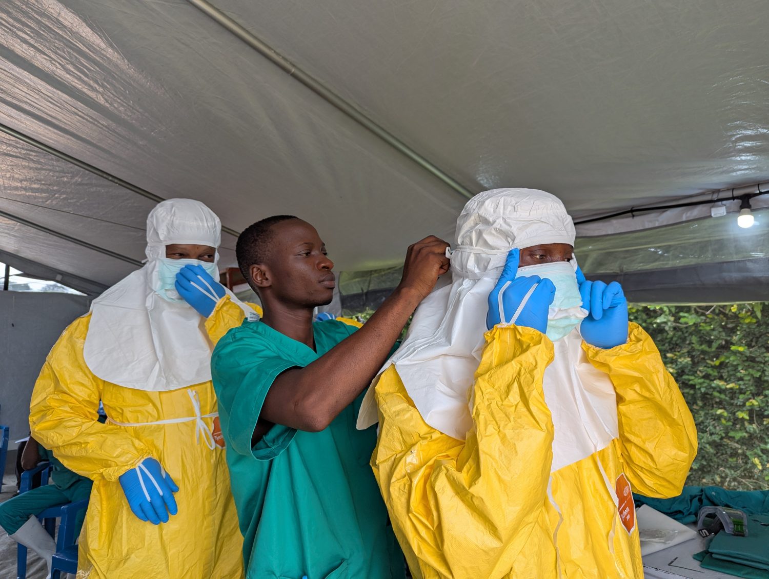 Los miembros del personal del Centro de Tratamiento del Ébola del Hôpital du Cinquantenaire, en Kisangani, ayudan a sus colegas a ponerse el equipo de protección personal (EPP) antes de ingresar a la zona de alto riesgo.